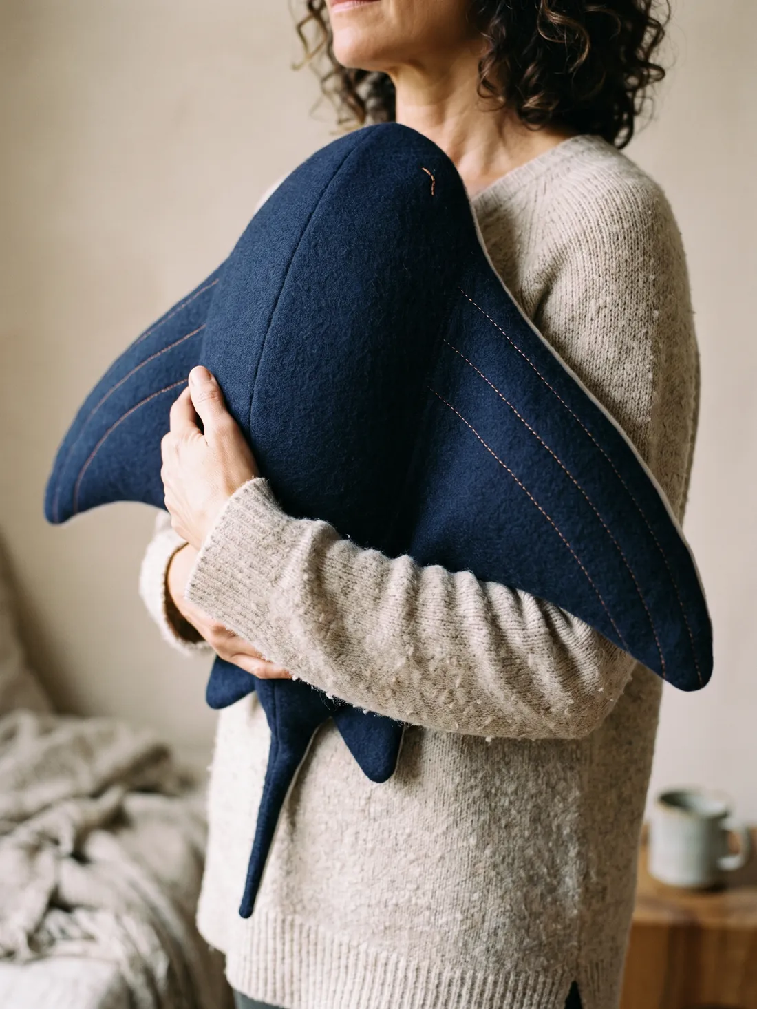 A woman holding Cove against her chest with both arms, its tail hanging down